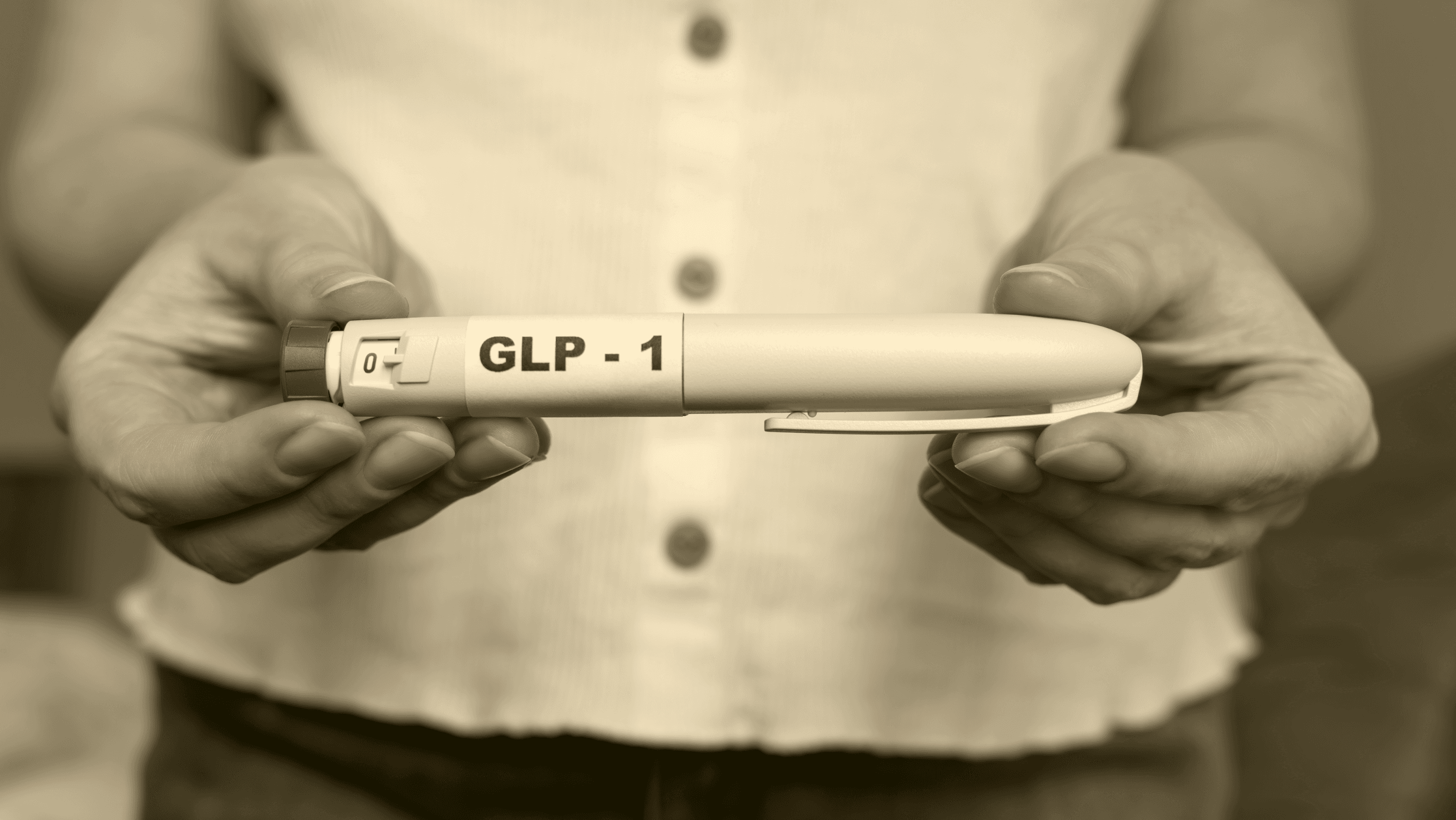 Sepia-toned close-up of hands holding a GLP-1 pen device