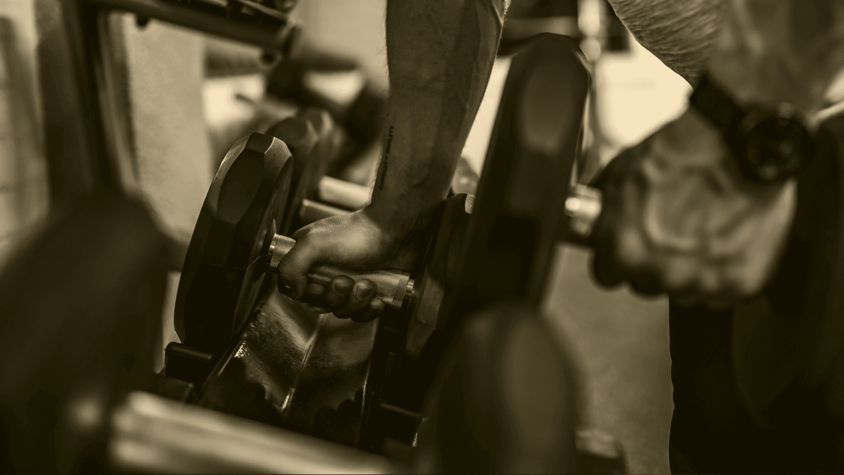 Sepia-toned close-up of a person lifting a dumbbell, representing strength training and adaptive stress